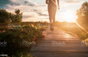 Close up of unknown woman running in park at sunset.